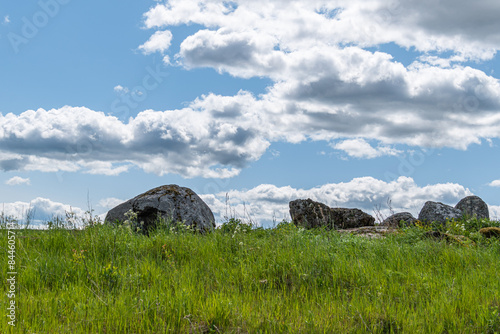 big boulders in green grass, cloudy sky