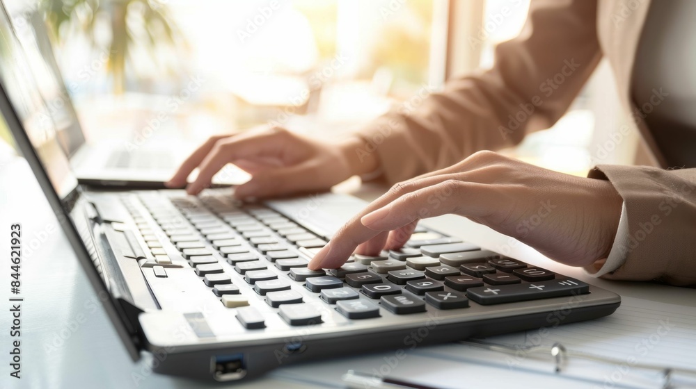 A person's hands typing on a laptop keyboard with sunlight streaming through a window. A person's hands typing on a laptop keyboard with sunlight streaming through a window.