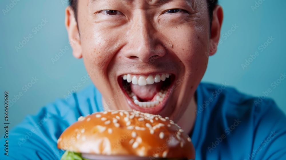 Man with open mouth showing teeth about to take a bite of a large sesame seed-topped burger. Man with open mouth showing teeth about to take a bite of a large sesame seed-topped burger.