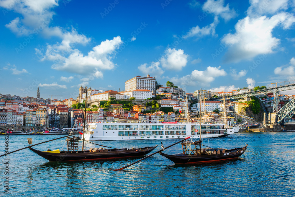 Obraz premium View of Porto city and Douro river with traditional boats with port wine barrels and sailing ship from famous tourist viewpoint Marginal de Gaia riverfront. Porto, Vila Nova de Gaia, Portugal
