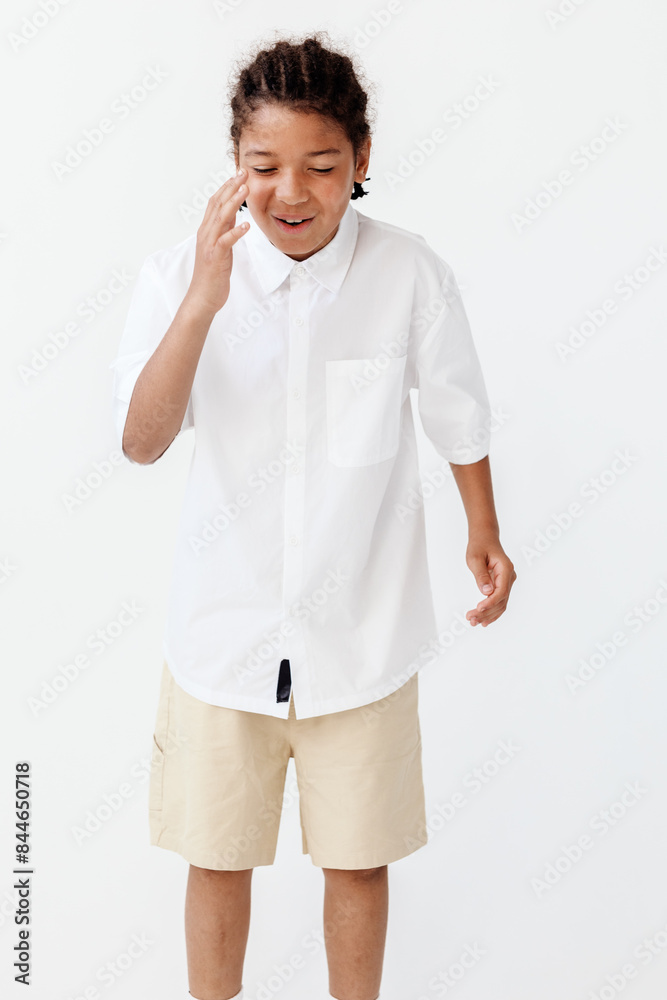 Young boy in white shirt and khaki shorts chatting happily on his mobile phone in a trendy urban setting Young boy in white shirt and khaki shorts chatting happily on his mobile phone in a trendy urban setting