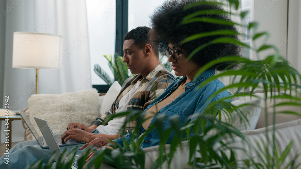 Gadget video game addict family computers addicted African American couple on couch at home ignoring using two laptops sad African American woman wife girlfriend looking on husband man exhale stress Gadget video game addict family computers addicted African American couple on couch at home ignoring using two laptops sad African American woman wife girlfriend looking on husband man exhale stress