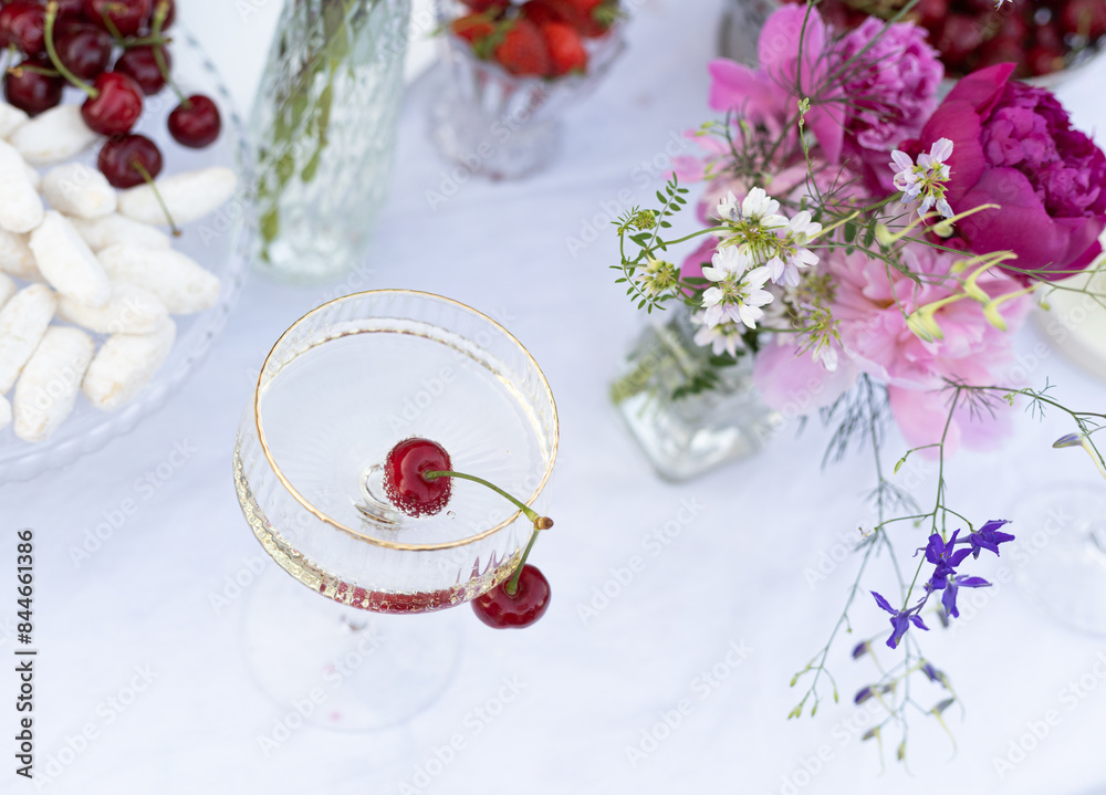 glass with champagne and cherry inside on table, decorated table glass with champagne and cherry inside on table, decorated table