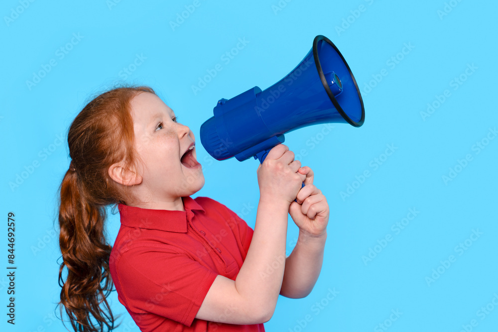 Young Girl Shouting Through A Blue Megaphone Against Light Blue Background Young Girl Shouting Through A Blue Megaphone Against Light Blue Background