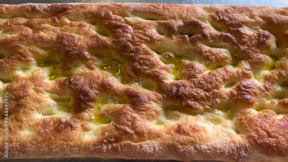 Focaccia with extra virgin olive oil, typical flat bread of Genoa, slide shot in top view