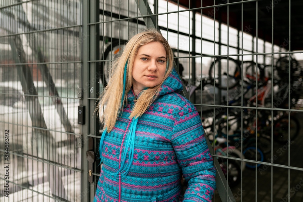 Fototapeta premium Blond woman in a blue winter jacket walks around the city