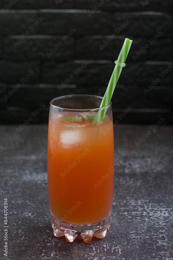 Grapefruit drink in a glass with a straw, mint and ice. Refreshing drink, freshly squeezed refreshing juice Grapefruit drink in a glass with a straw, mint and ice. Refreshing drink, freshly squeezed refreshing juice