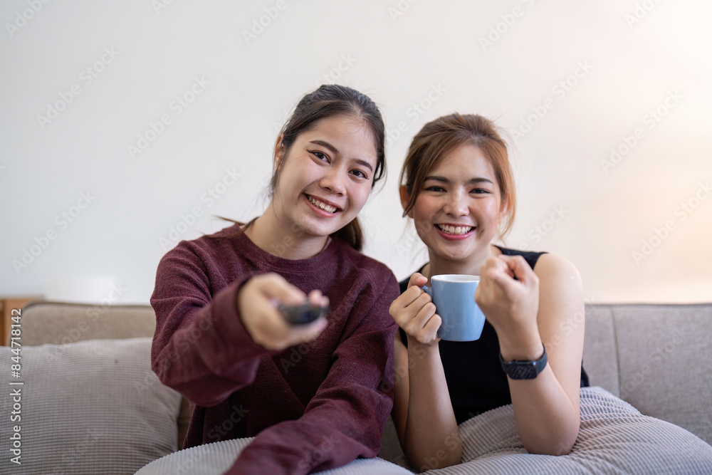 Happy Lesbian Couple Relaxing at Home, Watching TV and Drinking Coffee, LGBTQ Representation, Modern Lifestyle, Cozy Living Room Setting, Casual Clothing, Smiling and Enjoying Quality Time Together Happy Lesbian Couple Relaxing at Home, Watching TV and Drinking Coffee, LGBTQ Representation, Modern Lifestyle, Cozy Living Room Setting, Casual Clothing, Smiling and Enjoying Quality Time Together