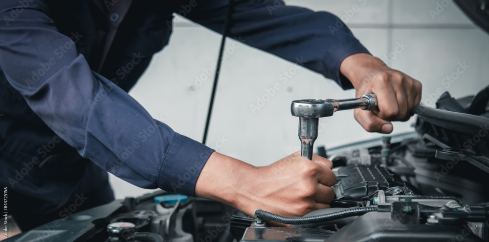 Mechanic using wrench while working on car engine outside the service center , Repair and service.