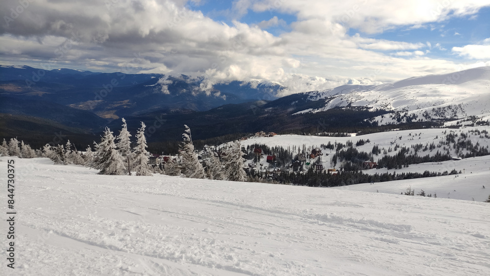 Fototapeta premium Drahobrat, ski resort, Carpatian mountains. Dramatic winter landscape, gloomy sky over the mountains. Panoramic winter nature. Snowy Carpatians, Ukraine. Mountain view, horizon over land, fir trees. 