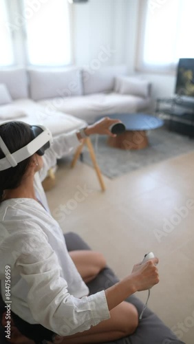A woman is immersed in virtual reality gaming using a VR headset in a stylish living room photo