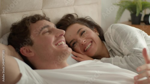 Caucasian couple man woman lying on bed home discussing plans chatting talking laughing happiness girlfriend boyfriend honeymoon romance togetherness intimate loving affection relax unity family smile