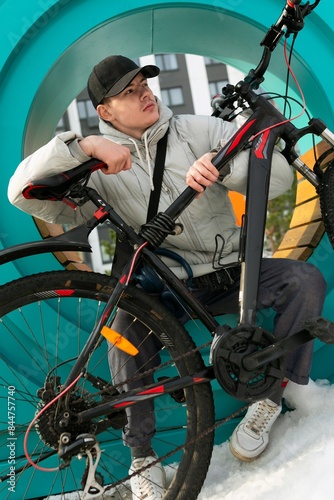 A man in a cap and a warm jacket enjoys a walk with a bicycle in the city