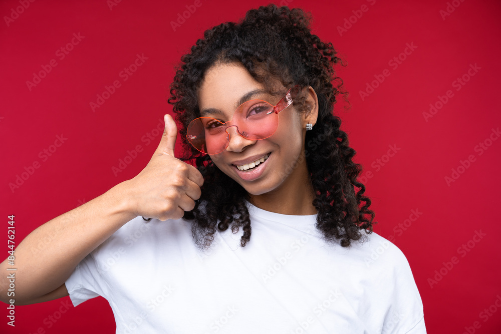 Portrait of a young girl smiling at the camera while standing against a red background. Portrait of a young girl smiling at the camera while standing against a red background.
