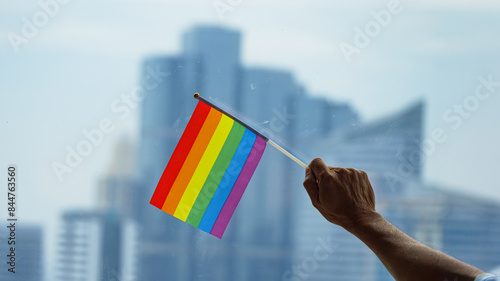 Office building background with a rainbow gay pride flag on the senior man's hand in the business office