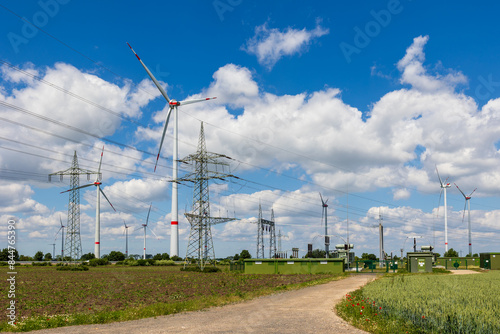 Windräder auf Feldern in Ostdeutschland, verbunden durch Stromleitungen und eine Umspannstation. Beitrag von Windkraft zur Energiewende und zum Energiemix. photo
