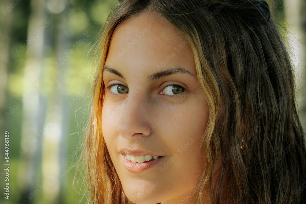 A woman with short hair gazes upward while standing in a birch tree forest. The sunlight filters through the trees, illuminating her face and creating a serene, contemplative mood.