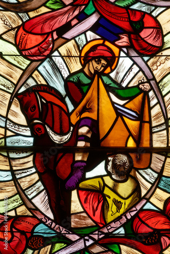 Stained glass of St. Martin sharing his cloak with a poor man. Vitrail de. Saint Martin à cheval partageant son manteau avec un pauvre. Annecy - France