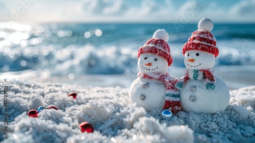 Two snowmen are standing on a beach with a red scarf around their necks