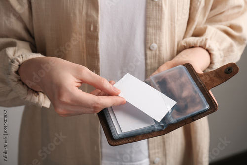 Woman holding leather business card holder and blank card on grey background, closeup © New Africa
