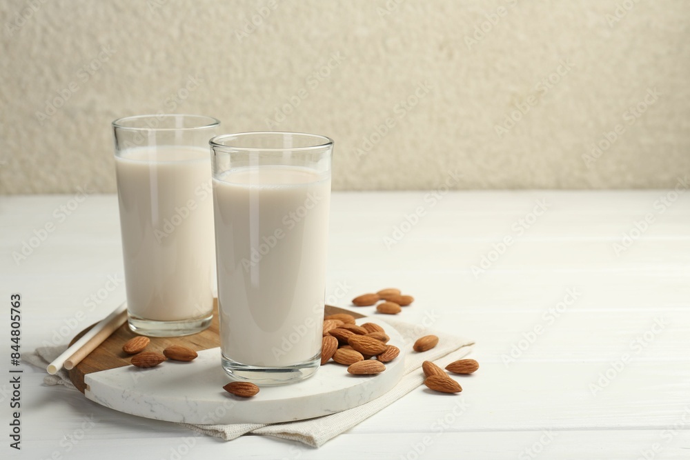 Glasses of almond milk and almonds on white wooden table, space for text Glasses of almond milk and almonds on white wooden table, space for text