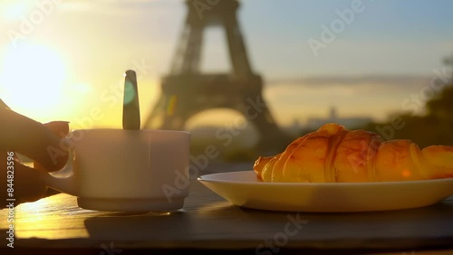 Hand stirs coffee in a cup with a spoon against the backdrop of the Eiffel Tower early in the morning. High quality 4k footage