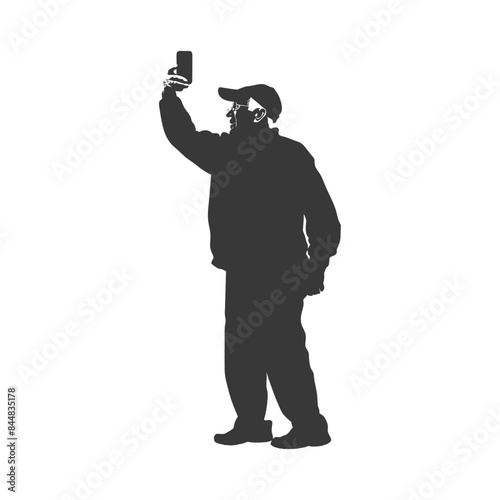 Silhouette: Man in cap, jacket, taking selfie with phone raised.
