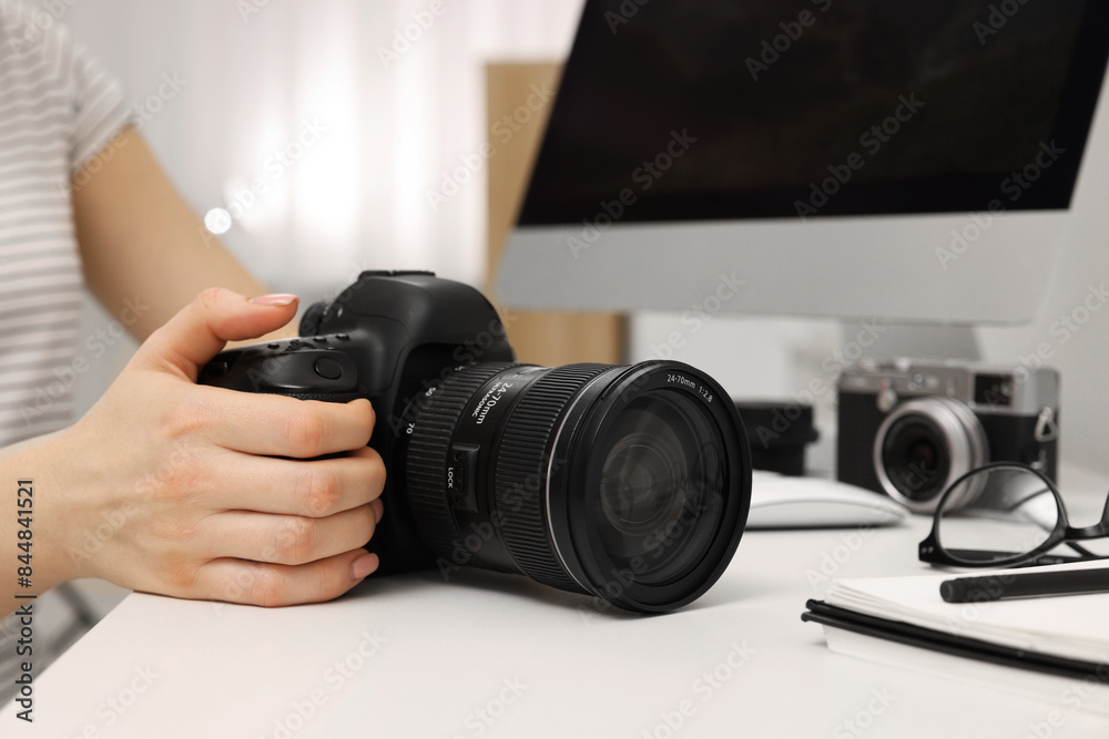 Photographer with camera at white table indoors, closeup Photographer with camera at white table indoors, closeup