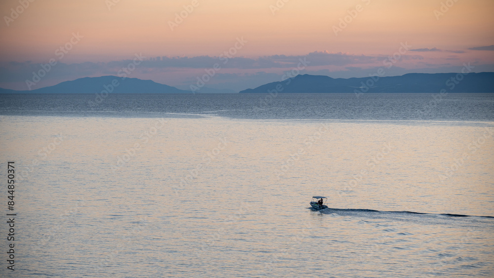 The boat sails across the sea towards the other shore at dusk The boat sails across the sea towards the other shore at dusk