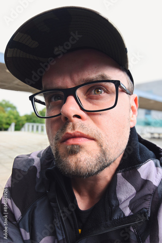 Obraz na płótnie Portrait of handsome serious looking young man with glasses, beard and cap, people background w salonie