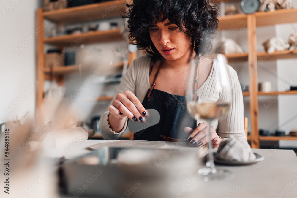 Portrait of pottery class attendee using scraper on her clay work. Portrait of pottery class attendee using scraper on her clay work.