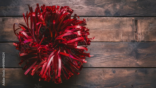 red cheerleader pompon on wooden surface