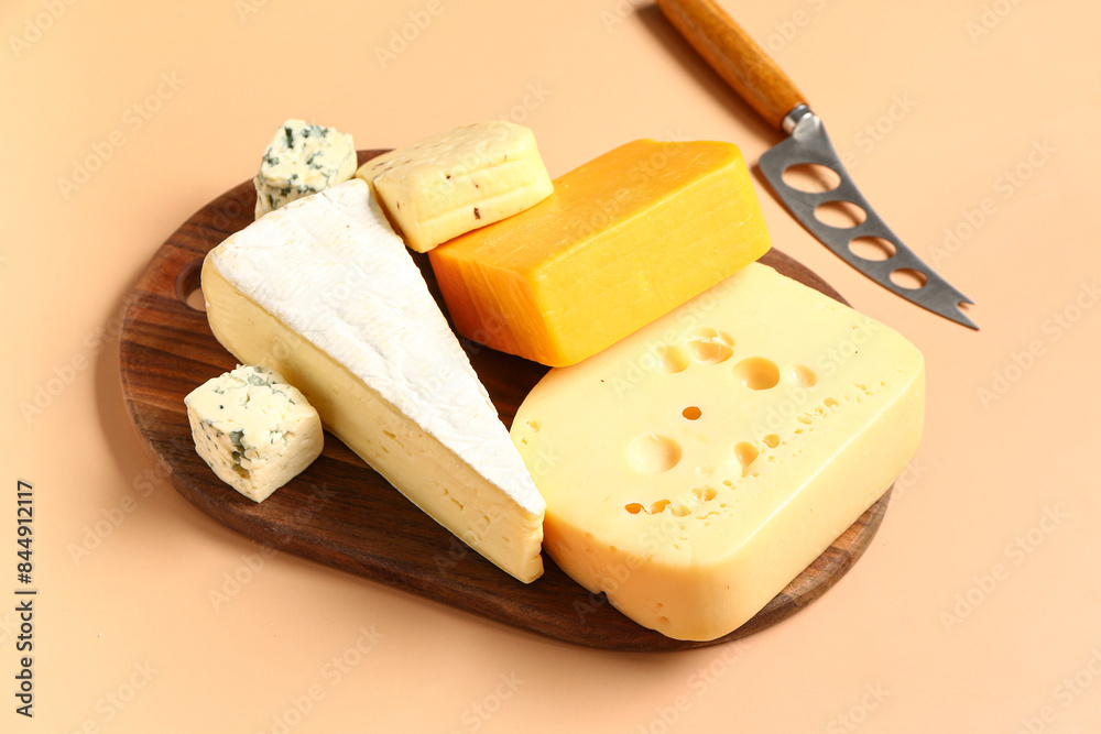 Fototapeta premium Wooden board with tasty cheese on beige background
