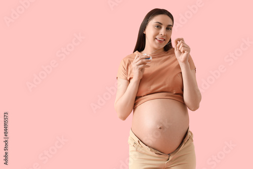 Young pregnant woman with dental floss on pink background photo