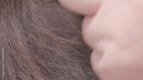 Parent's hands checking school-age child's hair for insects, searching for lice and nits, close-up head, importance of regular checks and preventive care
