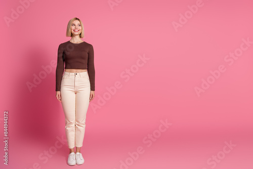 Full length photo of gorgeous cute girl wear stylish brown clothes look empty space isolated on pink color background