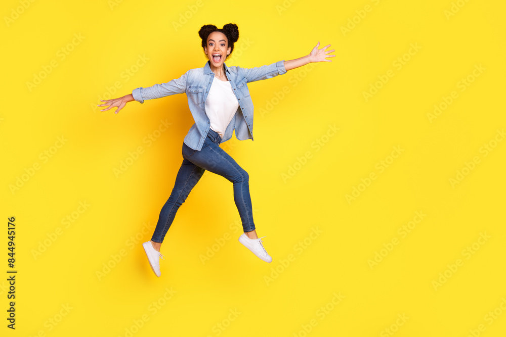 Full size photo of nice young girl jump empty space wear denim shirt isolated on yellow color background Full size photo of nice young girl jump empty space wear denim shirt isolated on yellow color background