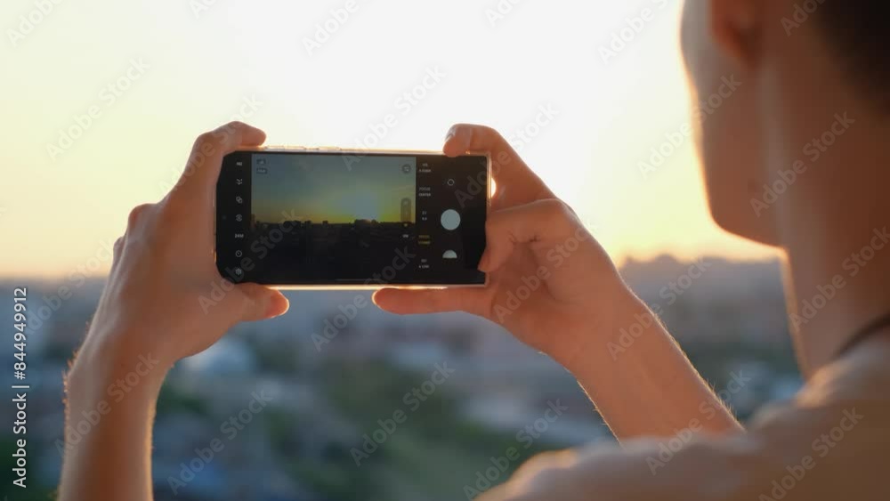 A man takes a photo of the city landscape at sunset on a smartphone A man takes a photo of the city landscape at sunset on a smartphone