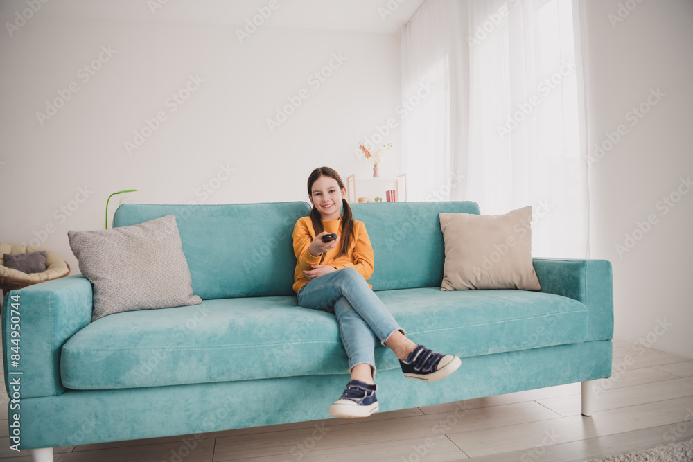 Obraz premium Portrait of lovely girl good mood sit couch watch tv hold remote control apartment indoors