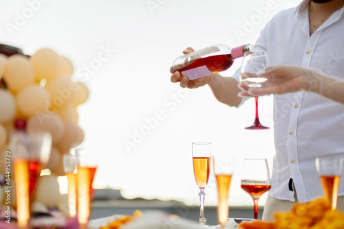 Bride and groom preparing for the bachelorette party pour white wine into glasses