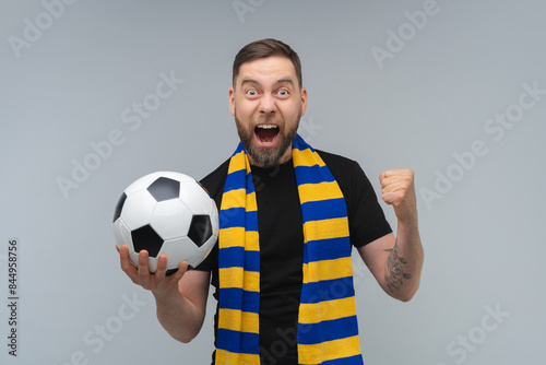 Obraz na plátně Studio portrait of euphoric soccer supporter man wearing yellow-blue scarf posin