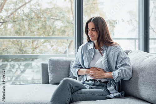 Foto Sick young woman in pain holding belly stomach feeling hurt abdomen ache gastritis pancreatitis symptoms or diarrhea, upset teen girl suffering from indigestion flatulence abdominal problem concept