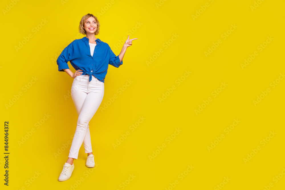 Full body portrait of pretty young lady indicate finger empty space wear shirt isolated on yellow color background Full body portrait of pretty young lady indicate finger empty space wear shirt isolated on yellow color background