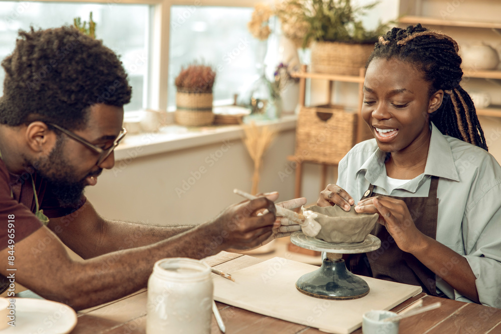Cute dark-skinned woman having a pottery master class with a male sculptor Cute dark-skinned woman having a pottery master class with a male sculptor
