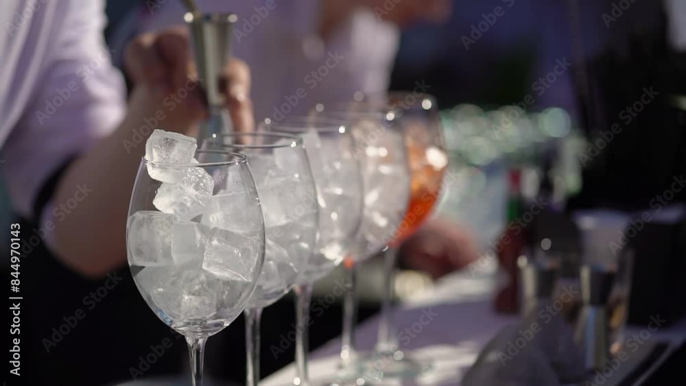 The waiter or bartender mixing cocktail in glasses. Welcome drink at a celebration or wedding reception in a restaurant or vacation bar. Alcoholic Beverage. Drinking straw.