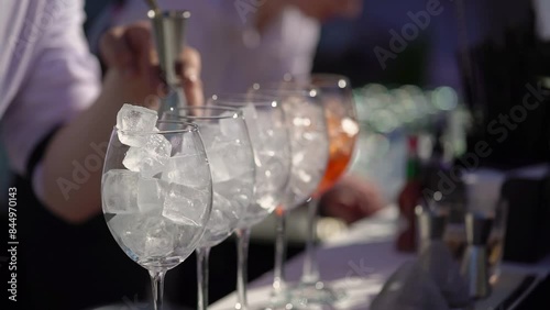 The waiter or bartender mixing cocktail in glasses. Welcome drink at a celebration or wedding reception in a restaurant or vacation bar. Alcoholic Beverage. Drinking straw.
