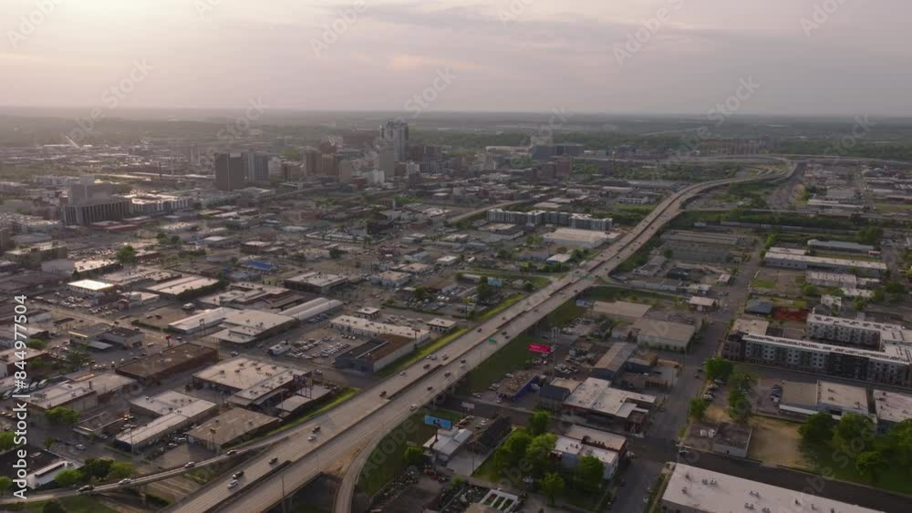 Aerial view of the highway in Birmingham, USA at sunrise, featuring cityscape, buildings, and cars passing through the city in clear weather with soft sunlight Aerial view of the highway in Birmingham, USA at sunrise, featuring cityscape, buildings, and cars passing through the city in clear weather with soft sunlight