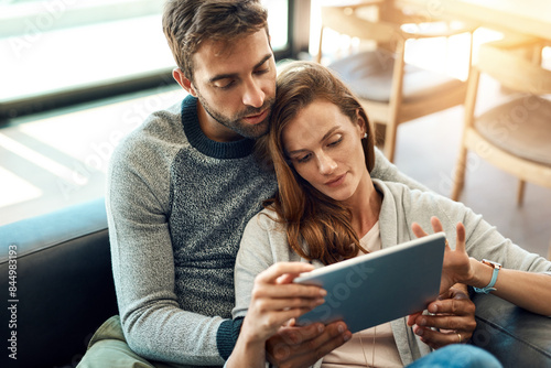 Search, man and woman with tablet on sofa for streaming, movie selection or tv choice at home. Calm, couple and discussion with technology and love embrace on couch for bonding and scrolling web app