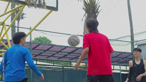 Young Asian Man Jumping And Shot The Ball To The Ring At Basketball Friendly Match photo