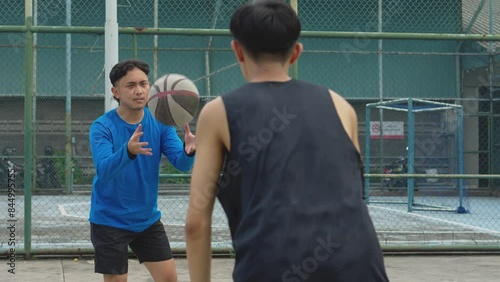 Young Asian Men Practicing Basketball By Bouncing The Ball At An Outdoor Court